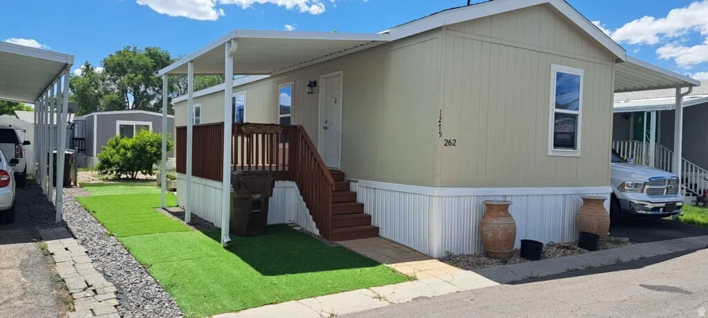Manufactured home featuring covered entry, exterior stairs, and a covered parking area