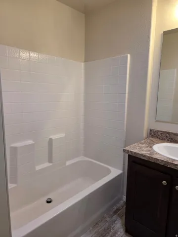 Full bathtub with white tiled surround in the master bedroom