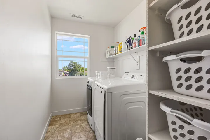 Dedicated laundry area featuring a window, built-in shelving, a wall-mounted shelf, and tile-finish flooring