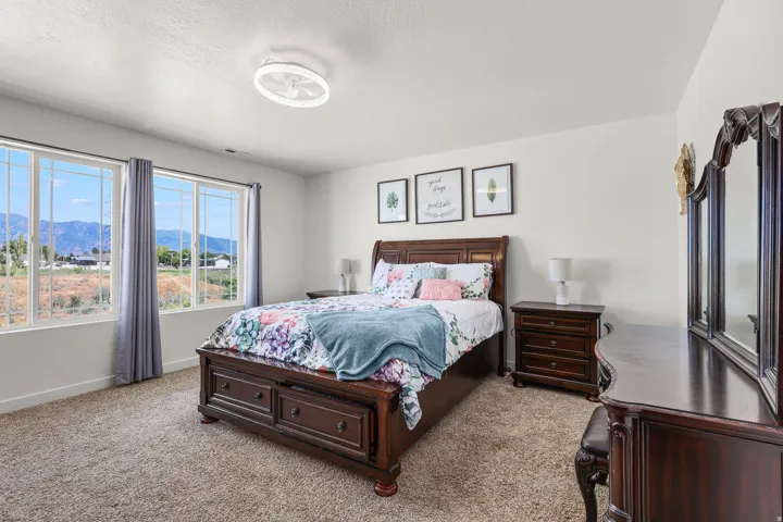 Expansive windows showcasing mountain scenery, complemented by plush carpet flooring, a contemporary ceiling light fixture, and white wall finishes
