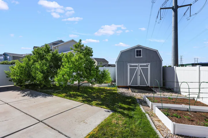 Barn-style storage shed with a small window, gravel landscaping, and raised garden beds