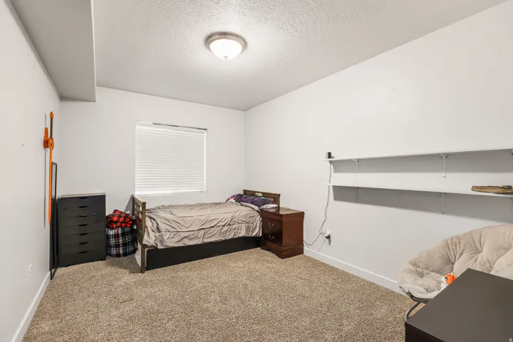 White walls, neutral carpet, and a window with blinds create a bright interior