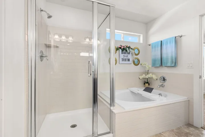 Bathroom featuring a glass-enclosed shower with white subway tile, a built-in tub with tile surround, and a clerestory window