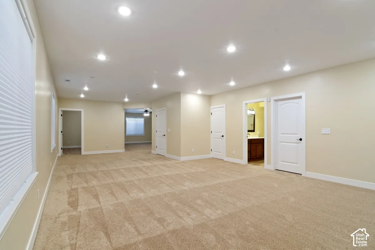 Expansive room featuring recessed lighting, neutral wall tones, and patterned carpeting
