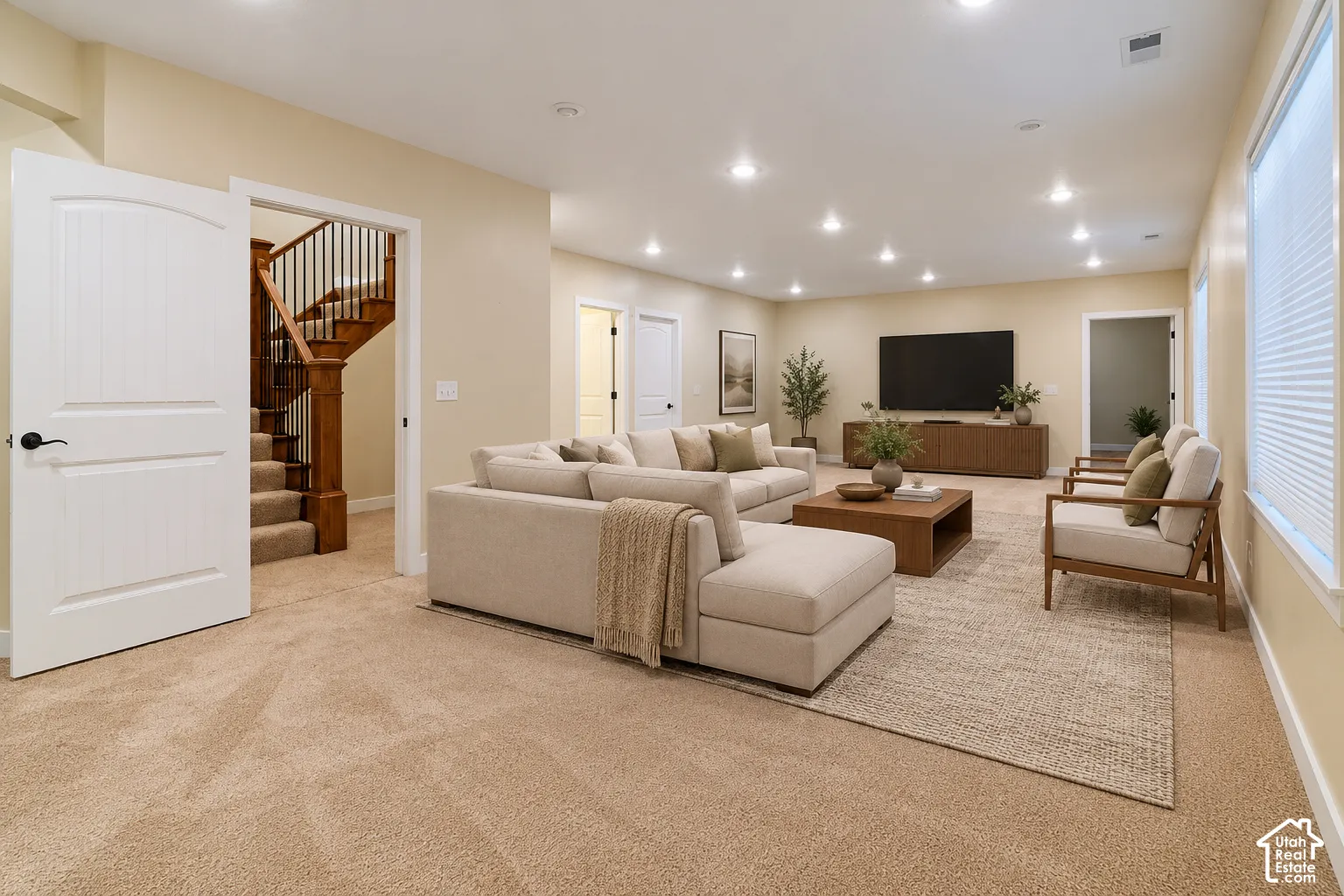 Spacious room featuring recessed lighting, wall-to-wall carpeting, and a staircase with stained wood railings and a decorative balustrade