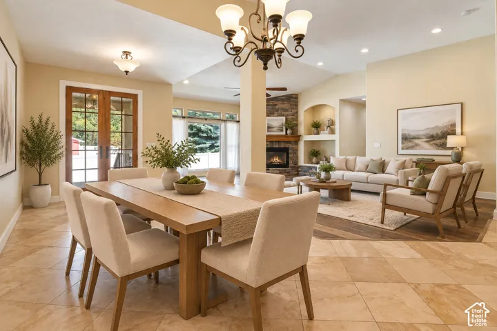 Open-concept area featuring stone-surround fireplace, dual built-in wall niches, multi-pane glass french doors, diagonal-patterned stone flooring, and recessed ceiling lighting