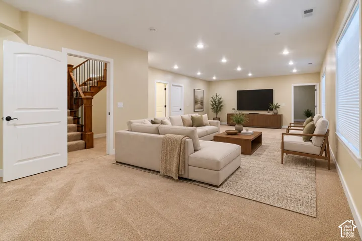 Spacious room featuring recessed lighting, wall-to-wall carpeting, and a staircase with stained wood railings and a decorative balustrade