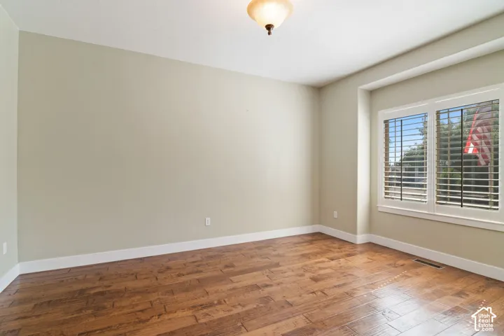 Spacious room featuring wood-finish flooring, light-toned walls, and white trim