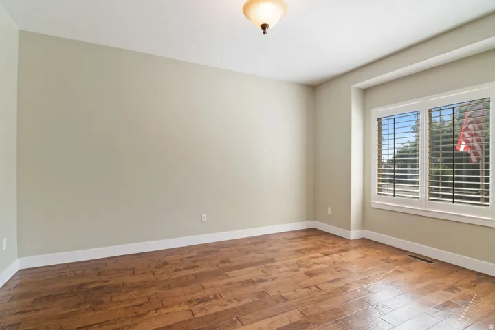 Spacious room featuring wood-finish flooring, light-toned walls, and white trim