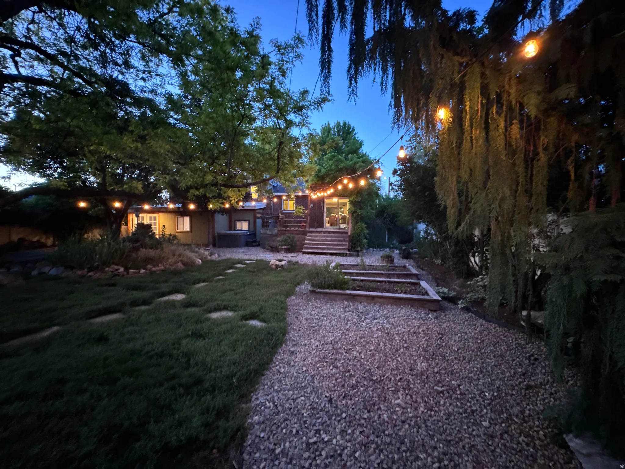 Expansive backyard featuring a gravel path, stepping stones, and a manicured alternative lawn