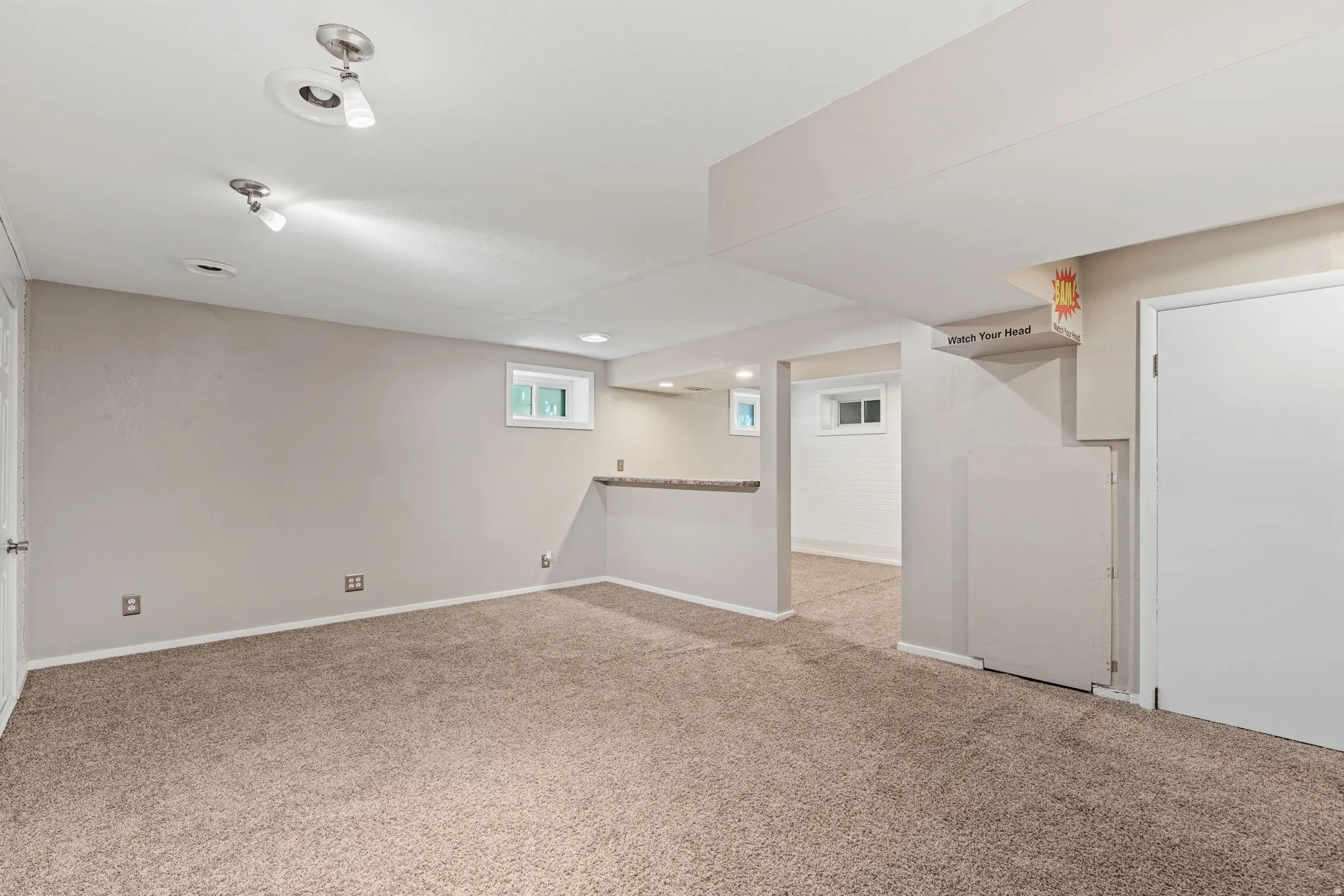 Carpeted room featuring track lighting, and a partial wall with a countertop