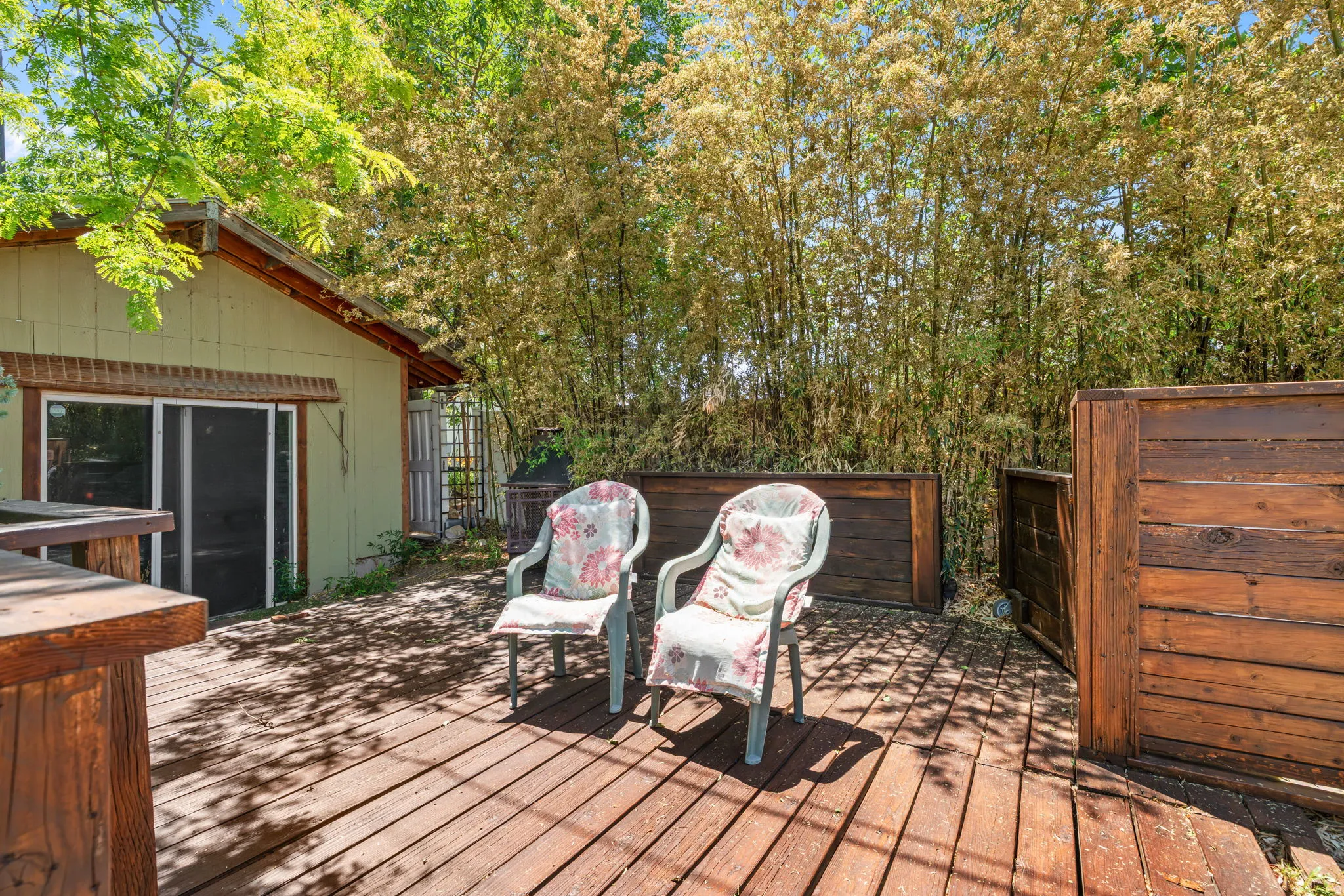 Expansive outdoor wood deck, privacy fencing, and mature foliage outside workshop