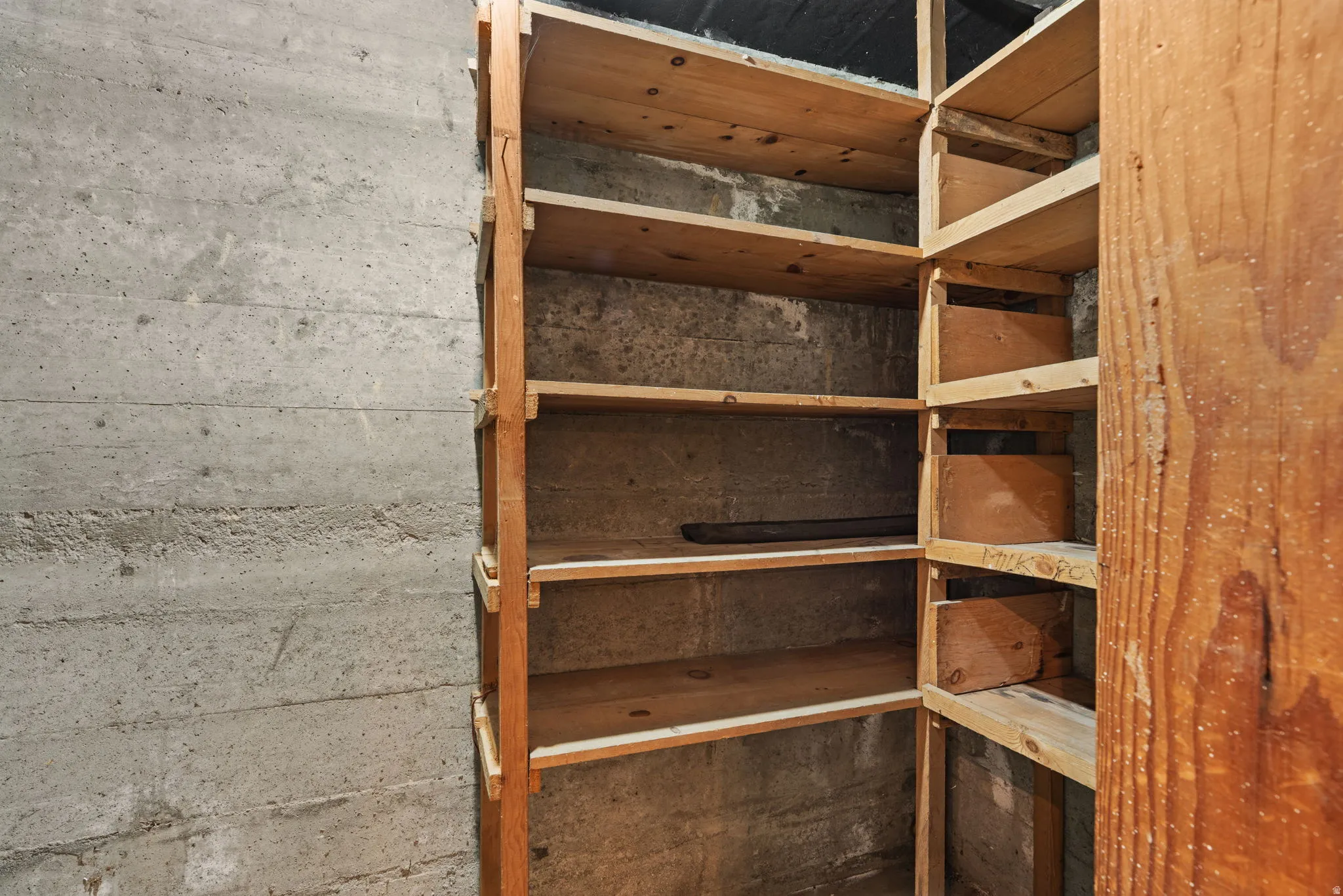 Built-in wood shelving units with multiple tiers set against a concrete wall