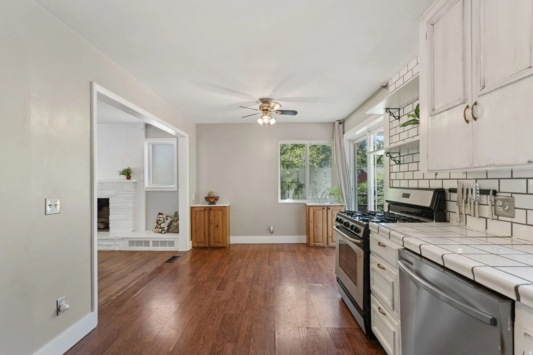 Kitchen area featuring white cabinets, subway tile backsplash, stainless steel gas range, stainless steel dishwasher, and tile countertops