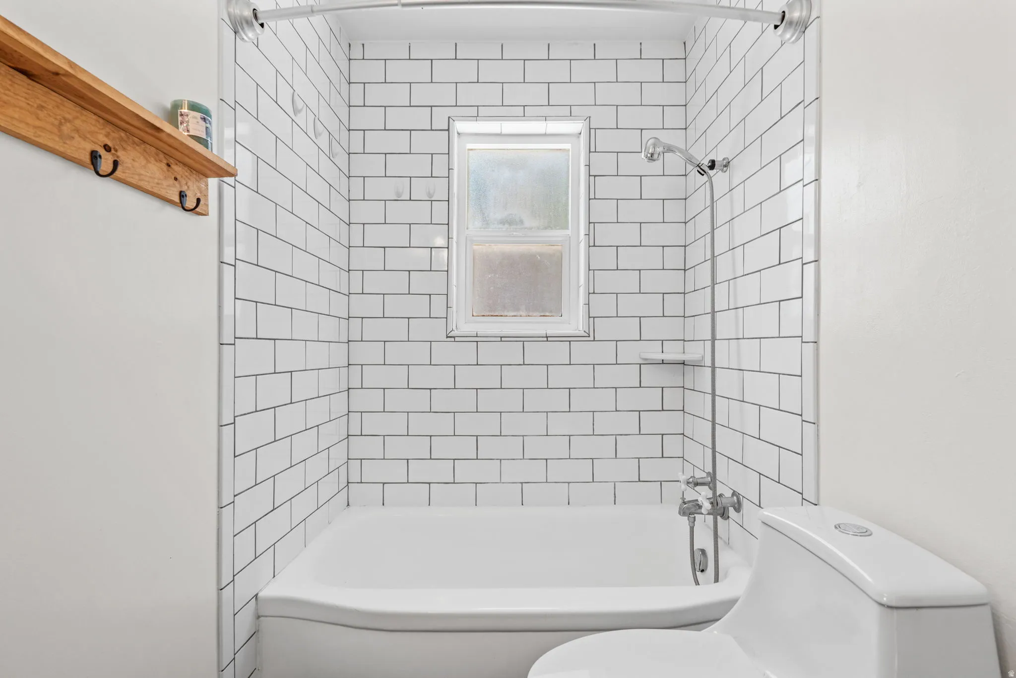 Bathroom featuring white subway tile surround, integrated bathtub, and shower fixture