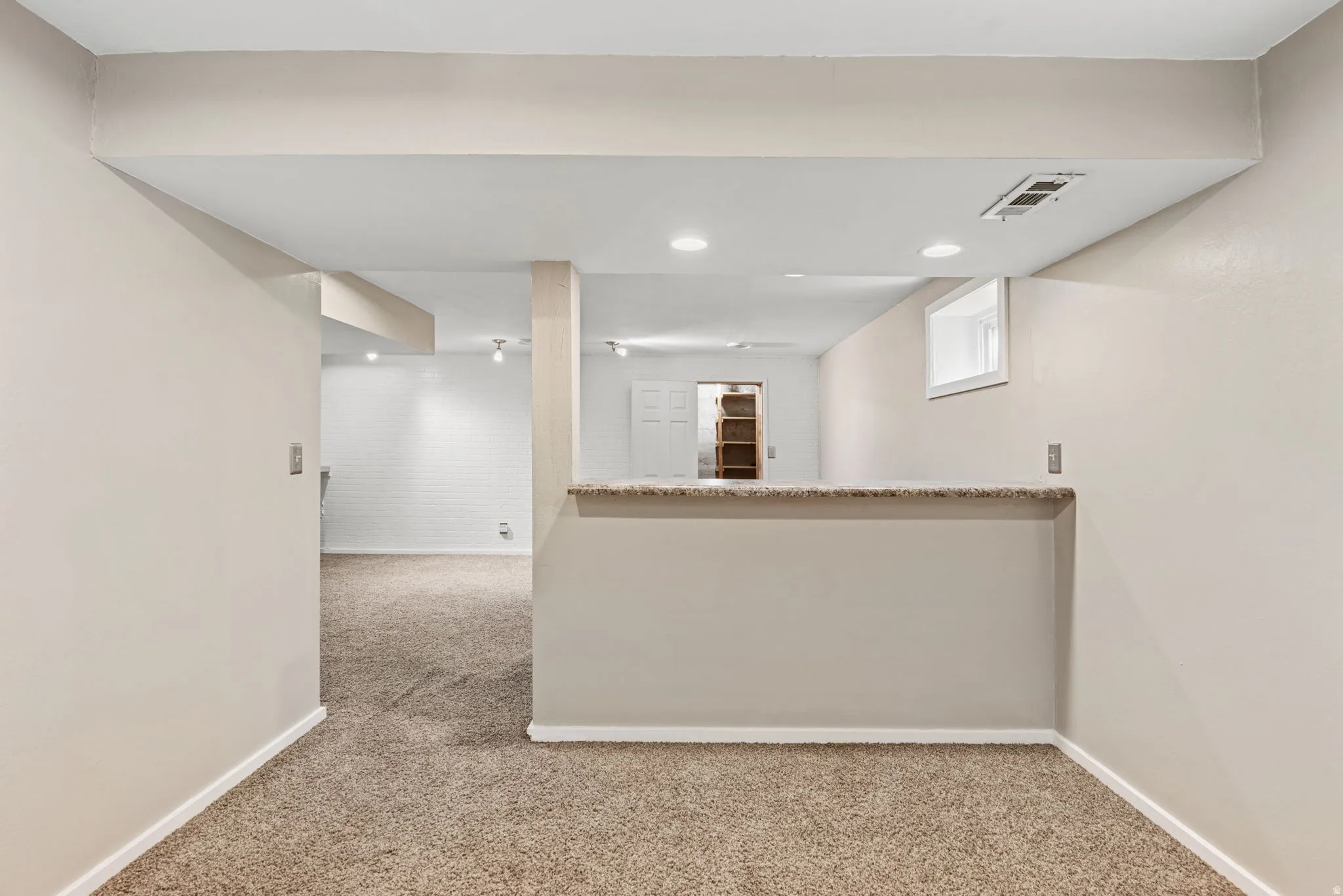 Carpeted room with recessed lighting and a half-wall with a countertop