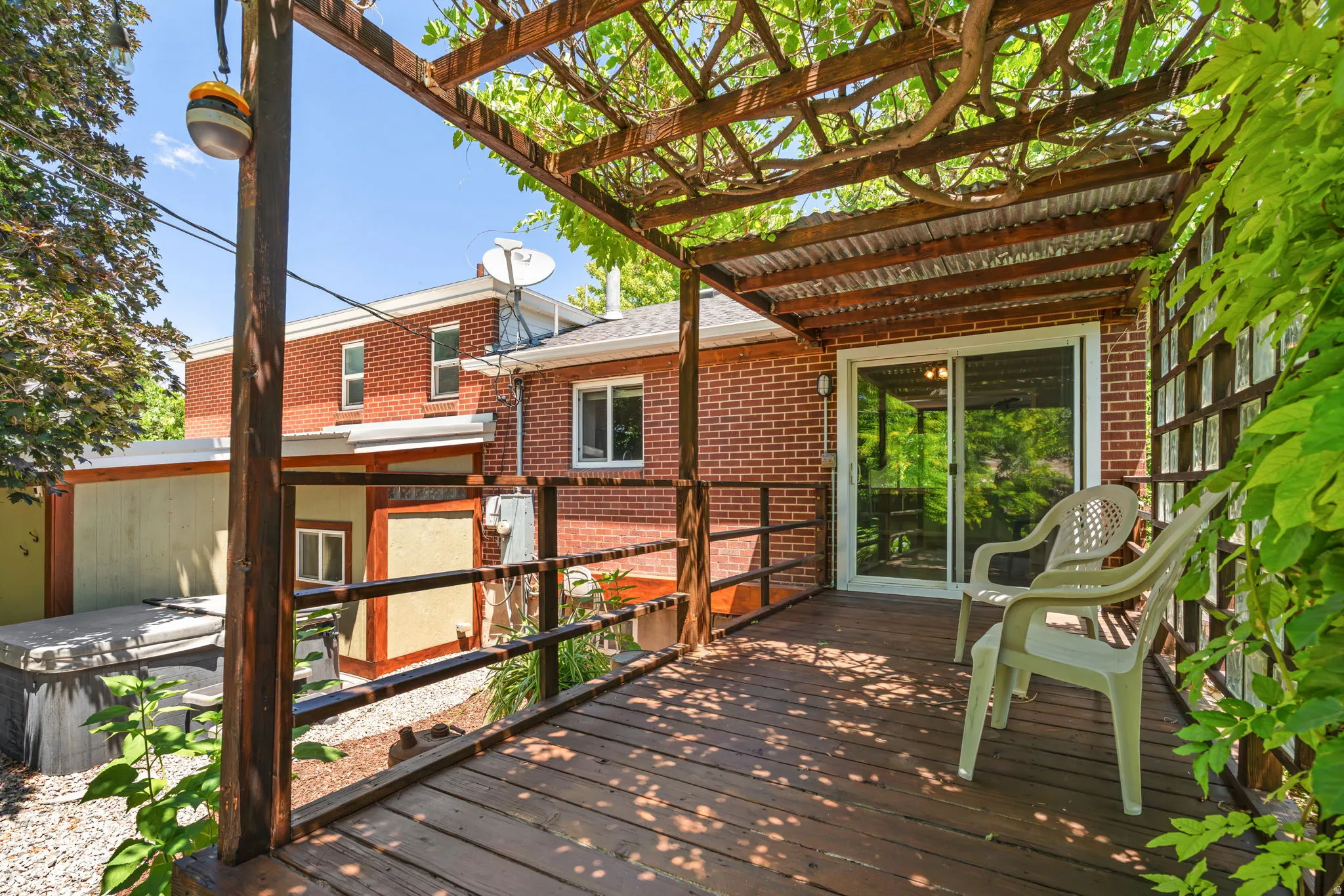 Expansive outdoor deck featuring a wood pergola with wisteria and a corrugated metal roof