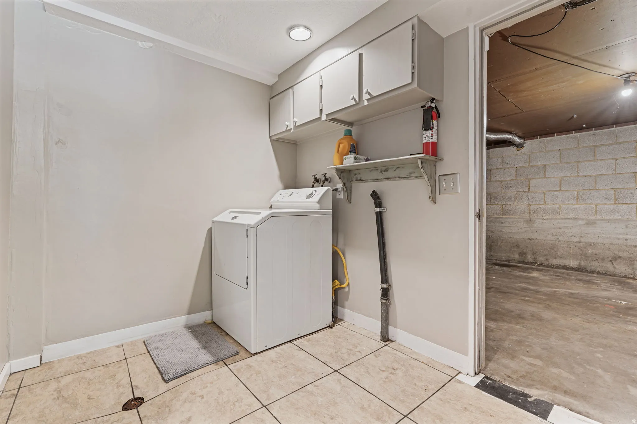 Laundry area featuring tiled flooring, recessed lighting, upper cabinetry, and a utility shelf with door to garage.