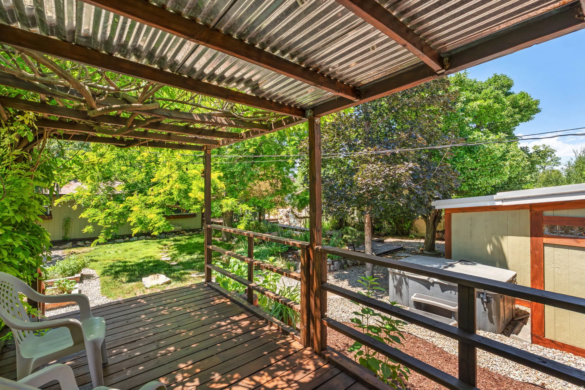 Expansive wood-decked patio with a corrugated metal roof and wooden pergola