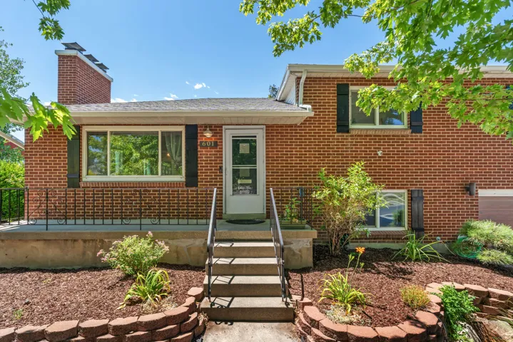Brick exterior featuring an entryway with metal railings and concrete steps