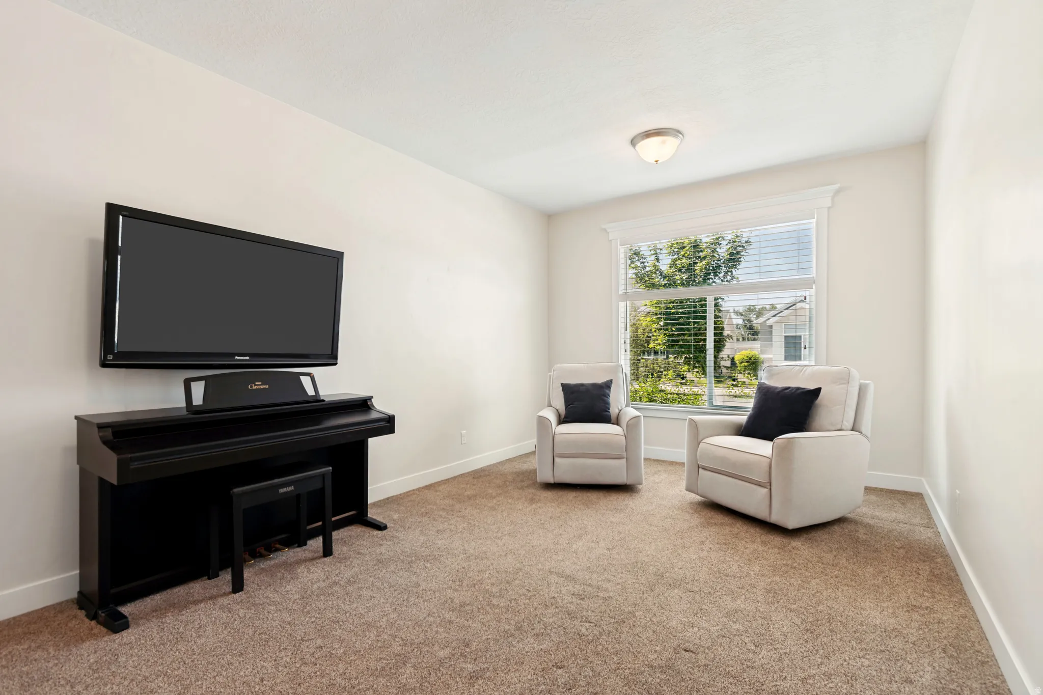 Carpeted room featuring a large window with white blinds, white trim, and a semi-flush mount ceiling light