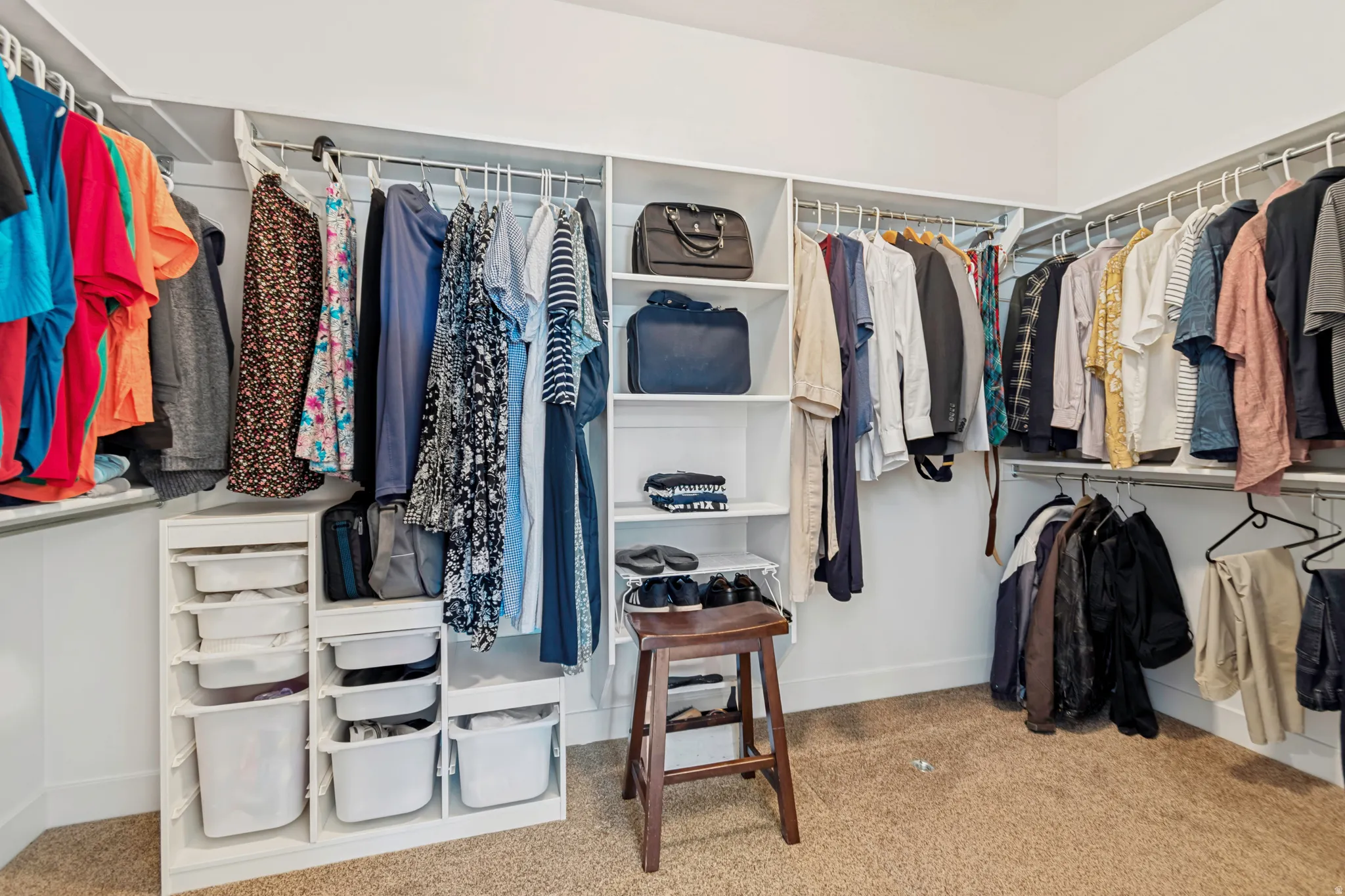 Walk-in closet featuring built-in shelving, multiple hanging rods, corner storage, and carpet flooring