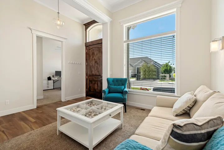 Spacious living area featuring a wood-finish entry door with an arched transom, a large picture window, and a decorative wall sconce