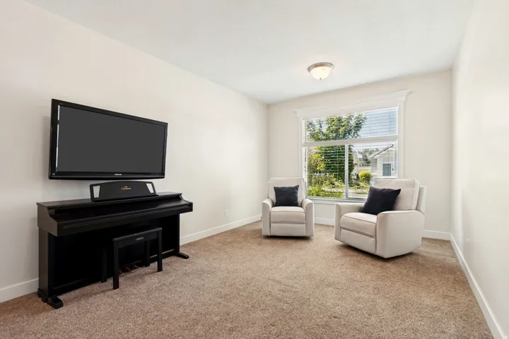 Carpeted room featuring a large window with white blinds, white trim, and a semi-flush mount ceiling light