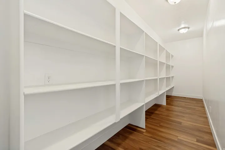 Built-in shelving system with white finish, wood-finish flooring, and two ceiling-mounted light fixtures