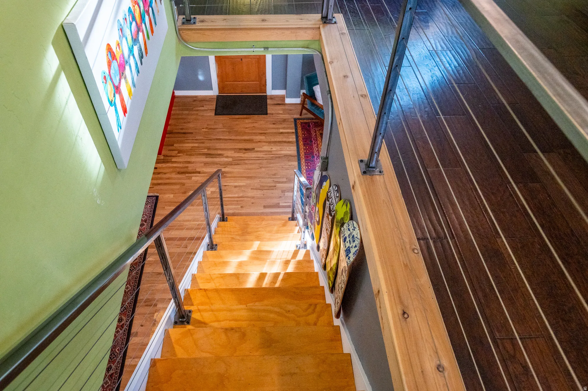 Hardwood staircase with industrial-style metal railings, complemented by hardwood flooring on both upper and lower levels