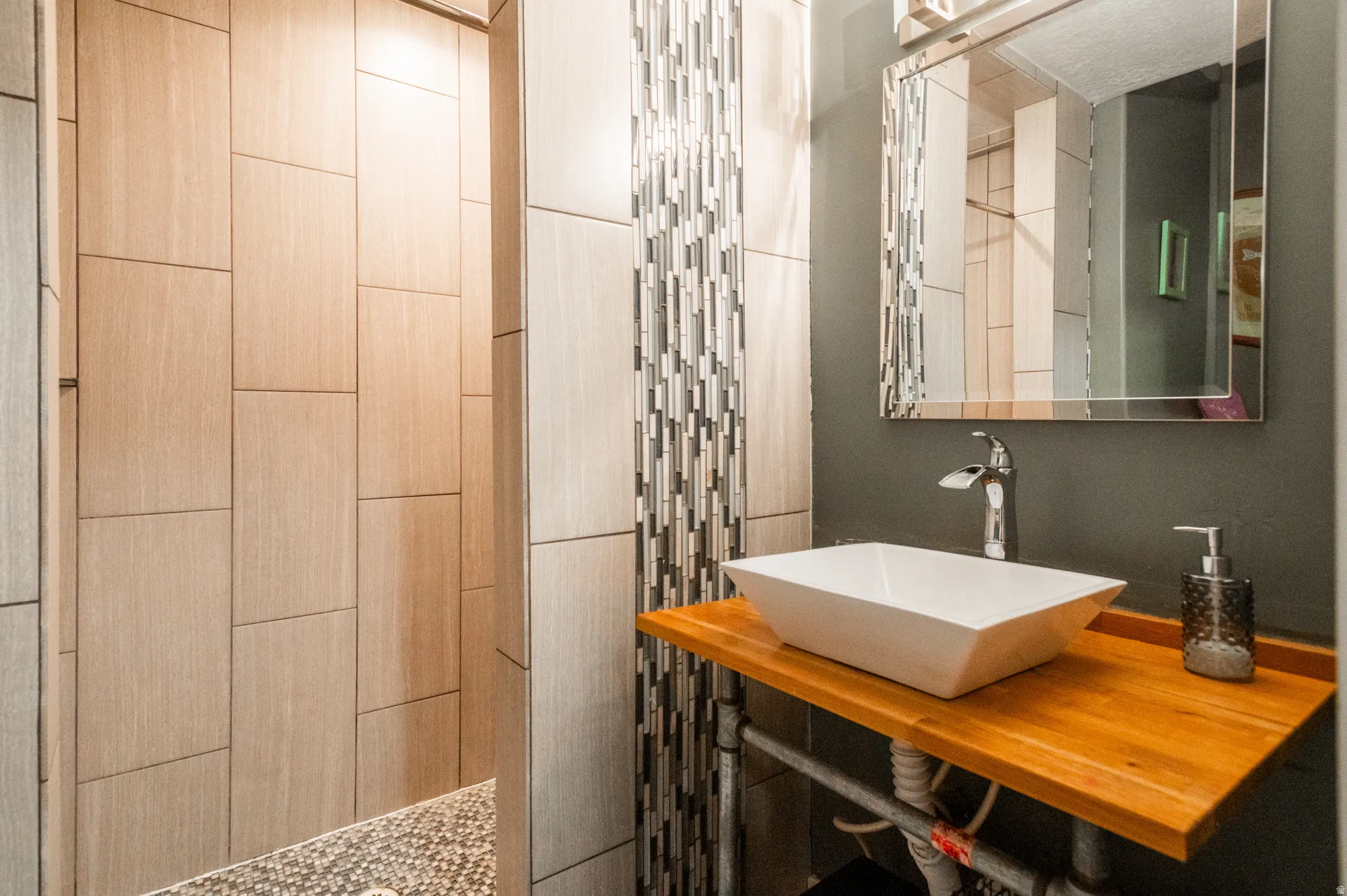 Contemporary bathroom featuring a vessel sink on a wood counter, chrome faucet, and a decorative mirror