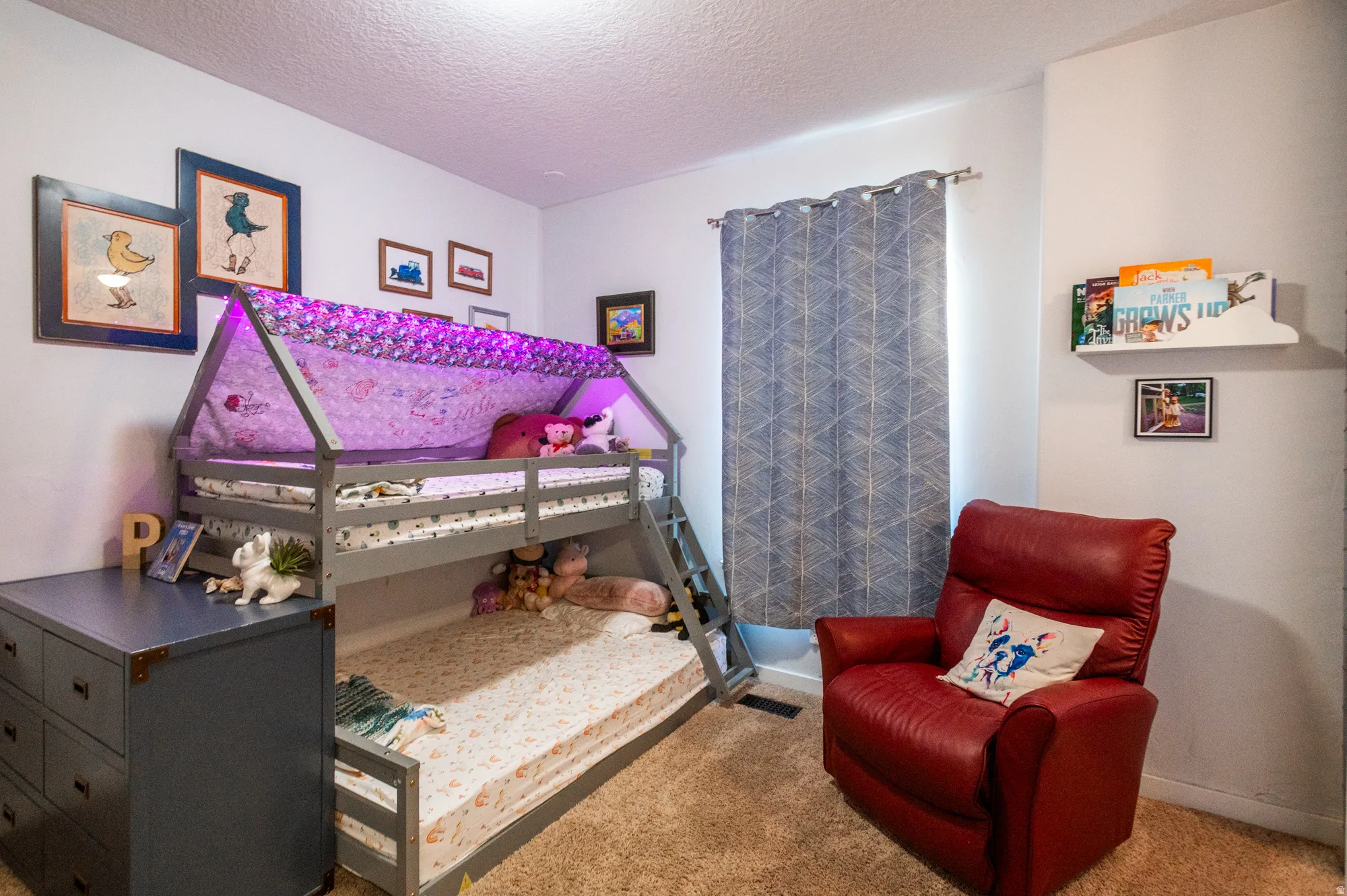 Carpeted room featuring a built-in bunk bed structure with an integrated ladder, a window with patterned drapes, and a wall-mounted display shelf