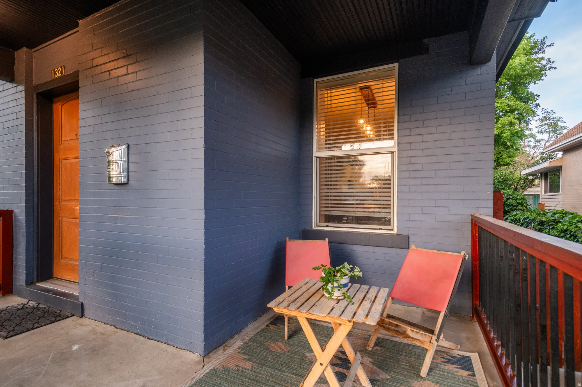 Covered porch with painted brick exterior, a wood entry door, and a single window with blinds