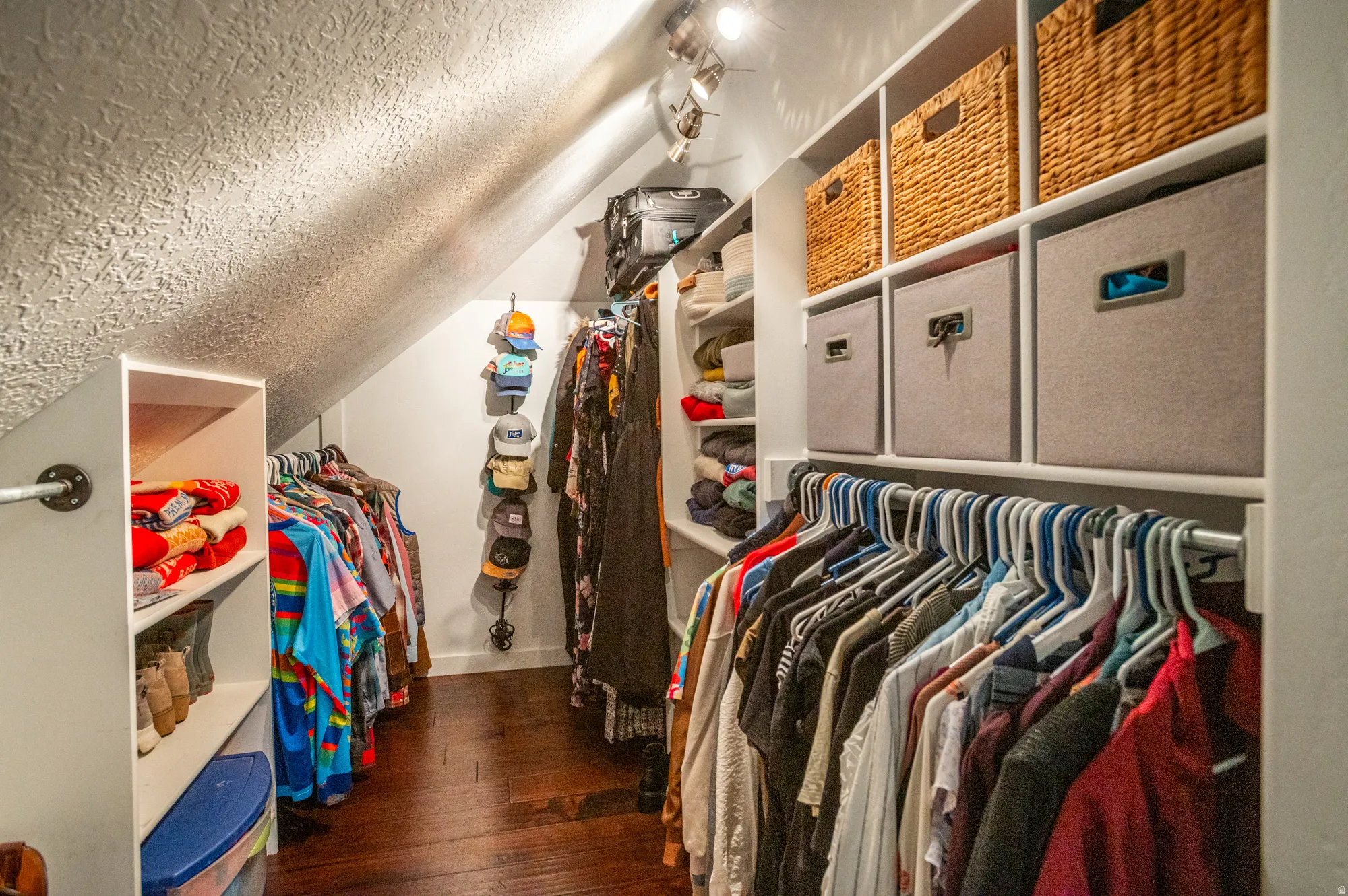 Custom closet organization system featuring built-in shelving, hanging rods, and dark wood-finish flooring