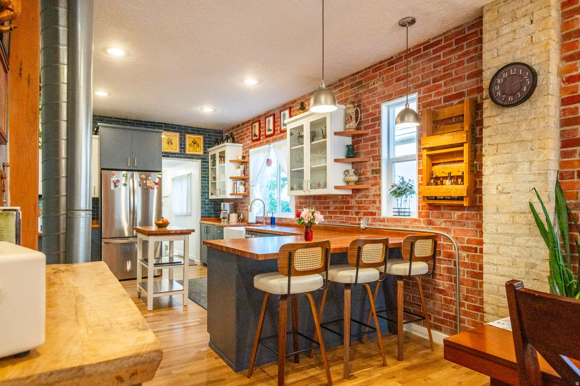 Expansive kitchen featuring exposed brick walls, wood-finish flooring, and recessed lighting