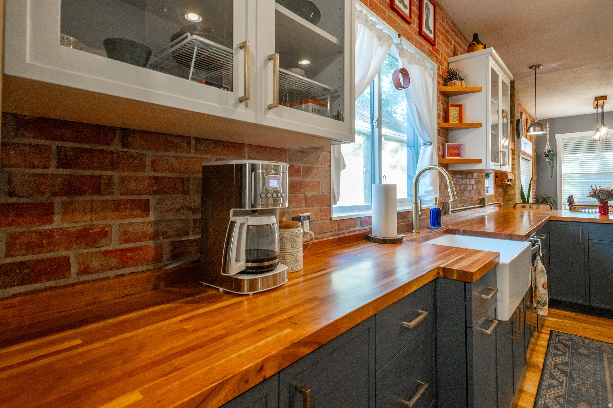 Butcher block countertops complement the exposed brick backsplash