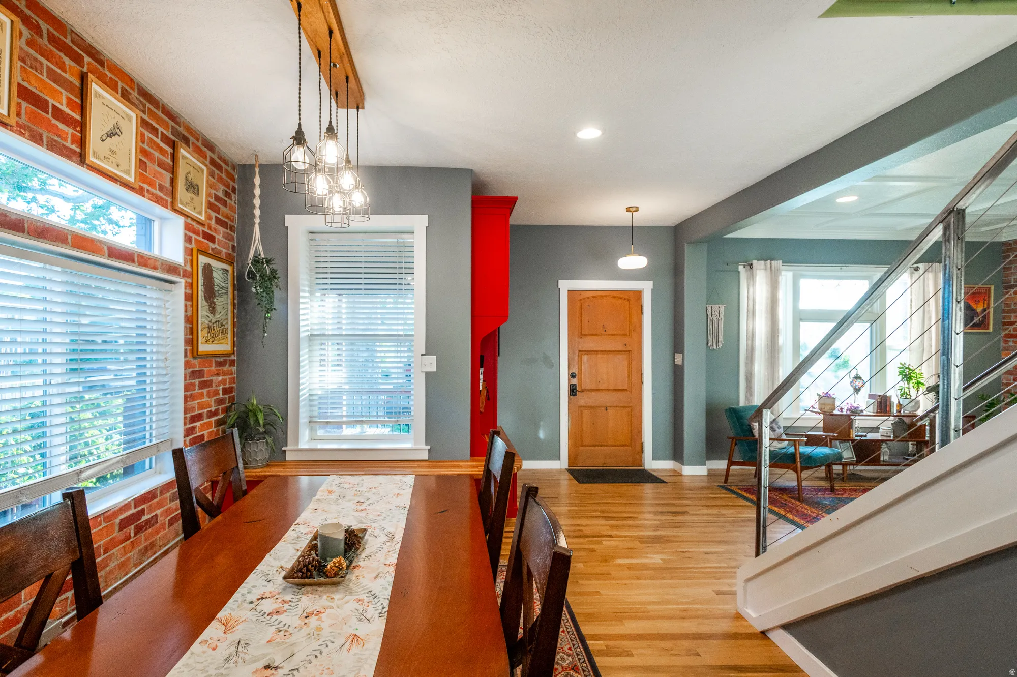 Spacious interior featuring wood-finish flooring, a brick accent wall, and multiple windows
