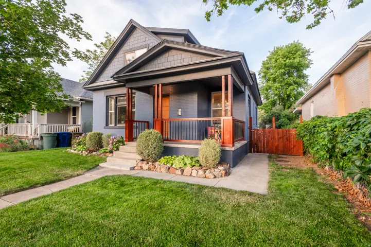 Exterior featuring a covered front porch with stained wood posts and railings, a gabled roofline, and a concrete walkway