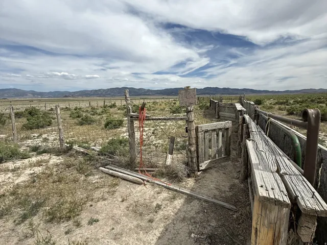 Expansive open terrain featuring a rustic wooden fence line and corrals