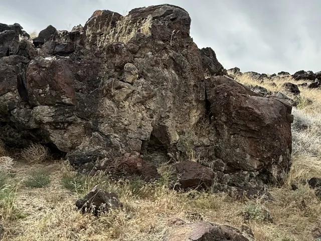 Rocky terrain featuring rugged dark rock formations and sparse dry grasses