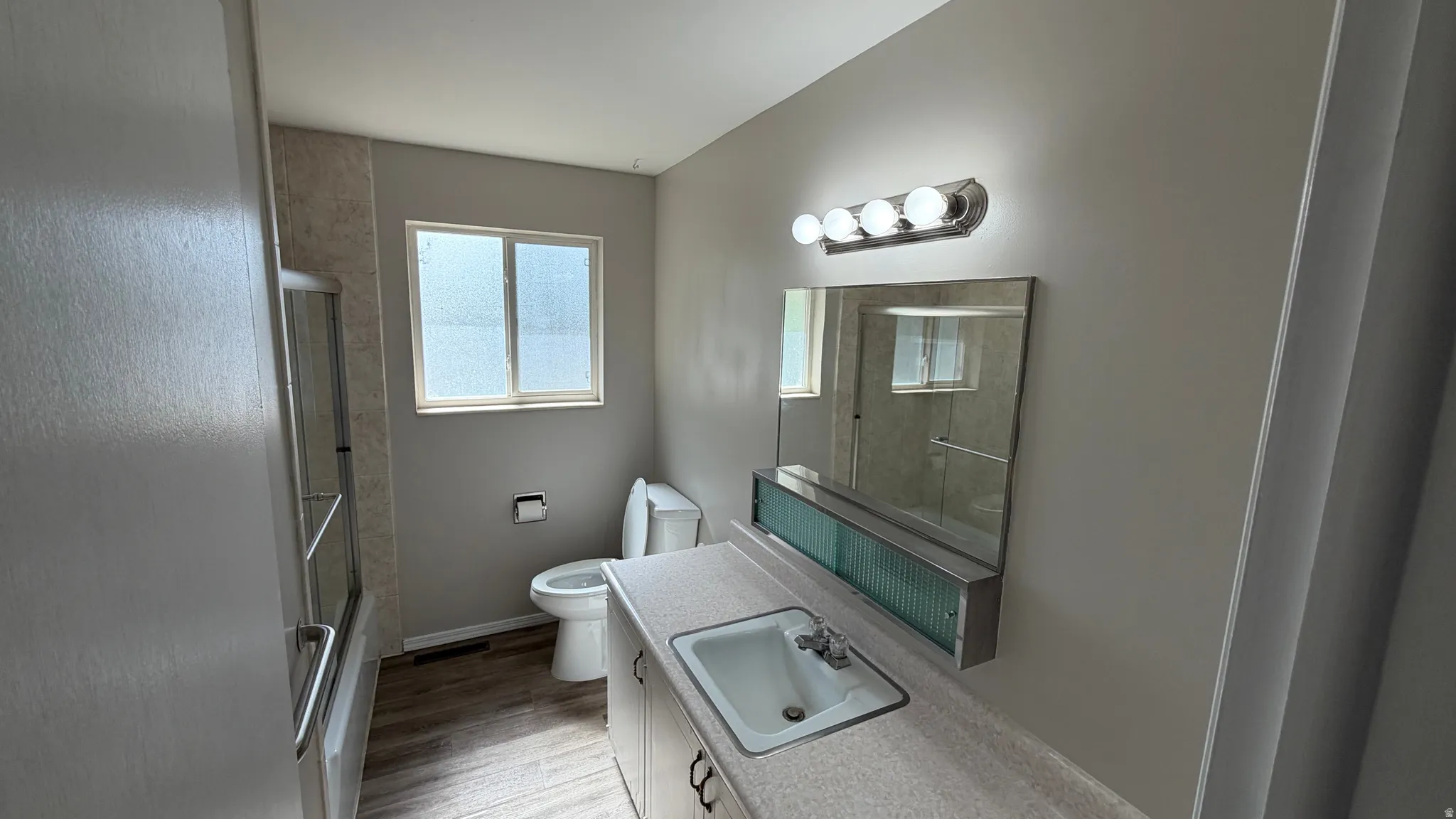 Bathroom with shower-tub combination, glass enclosure and tile tub surround