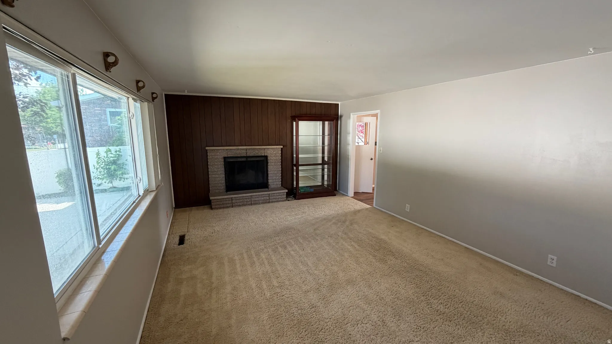 Spacious living room featuring a woodburning fireplace and large windows. China Cabinet Excluded