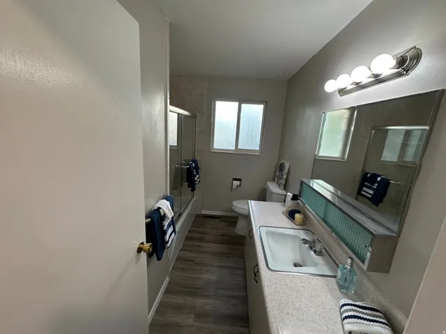 Bathroom featuring a single vanity with a laminate countertop, integrated sink, and an expansive mirror