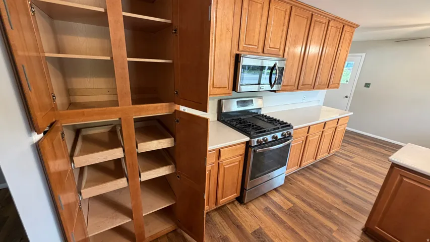 Light wood cabinetry, stainless steel gas range with micro-hood, and solid surface countertops