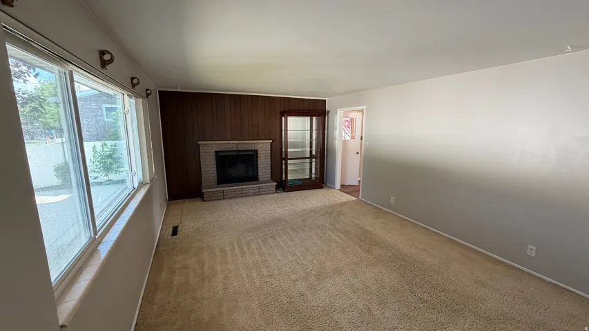 Spacious living room featuring a woodburning fireplace and large windows. China Cabinet Excluded