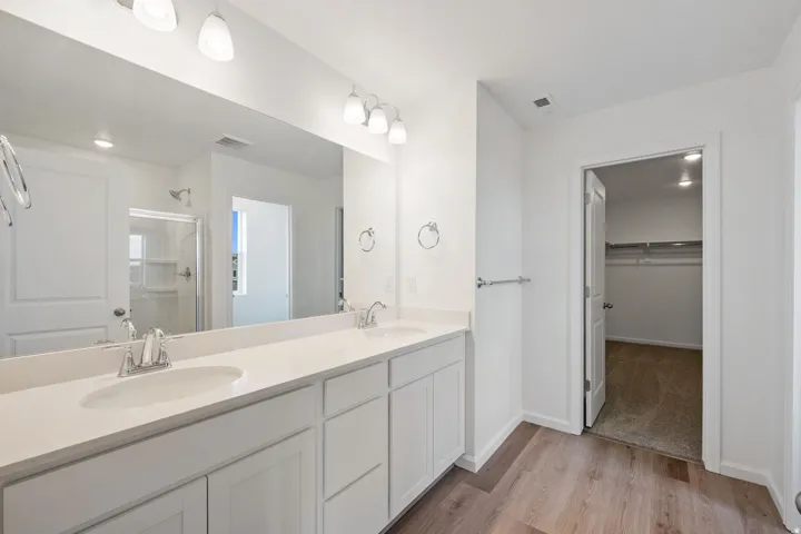 Double vanity with white cabinetry and integrated sinks set on wood-finish flooring