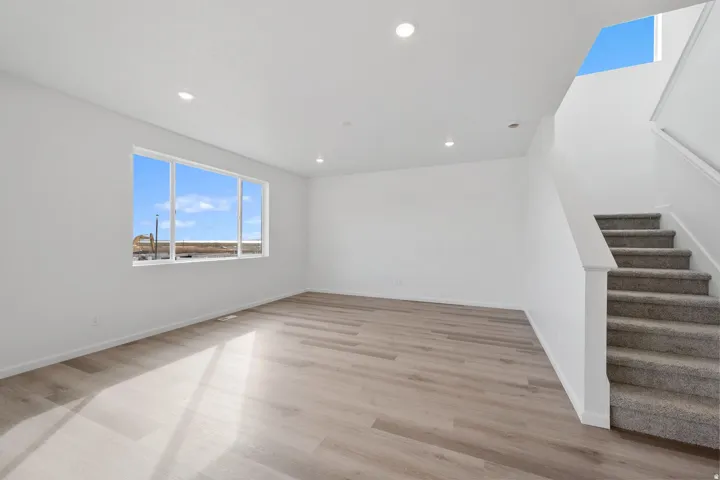 Spacious living area featuring wood-finish flooring, recessed lighting, and a large multi-pane window