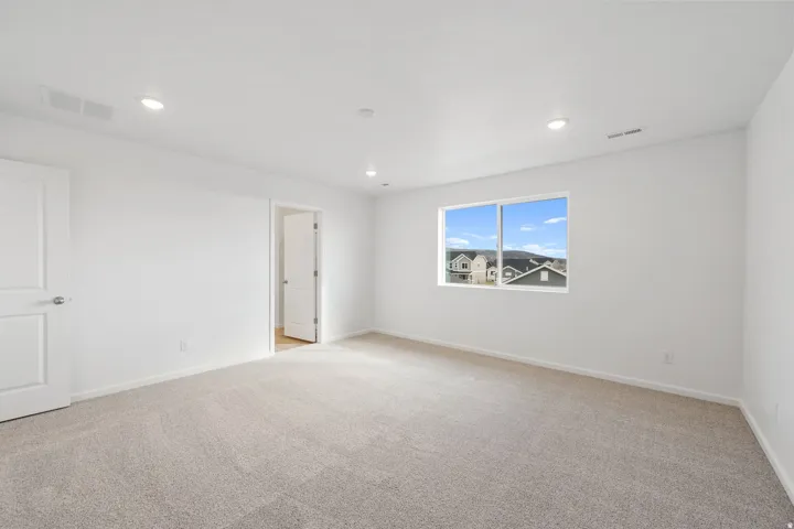 Spacious room featuring neutral carpeting and white walls
