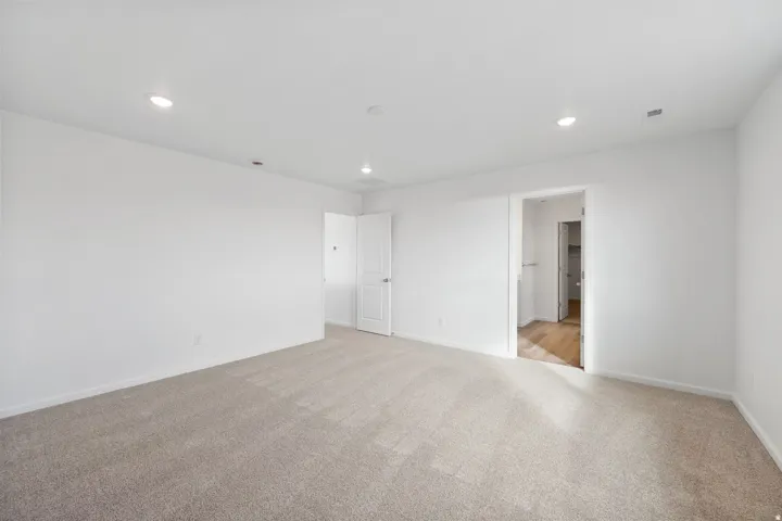 Carpeted room featuring white walls, recessed lighting, and a white interior door