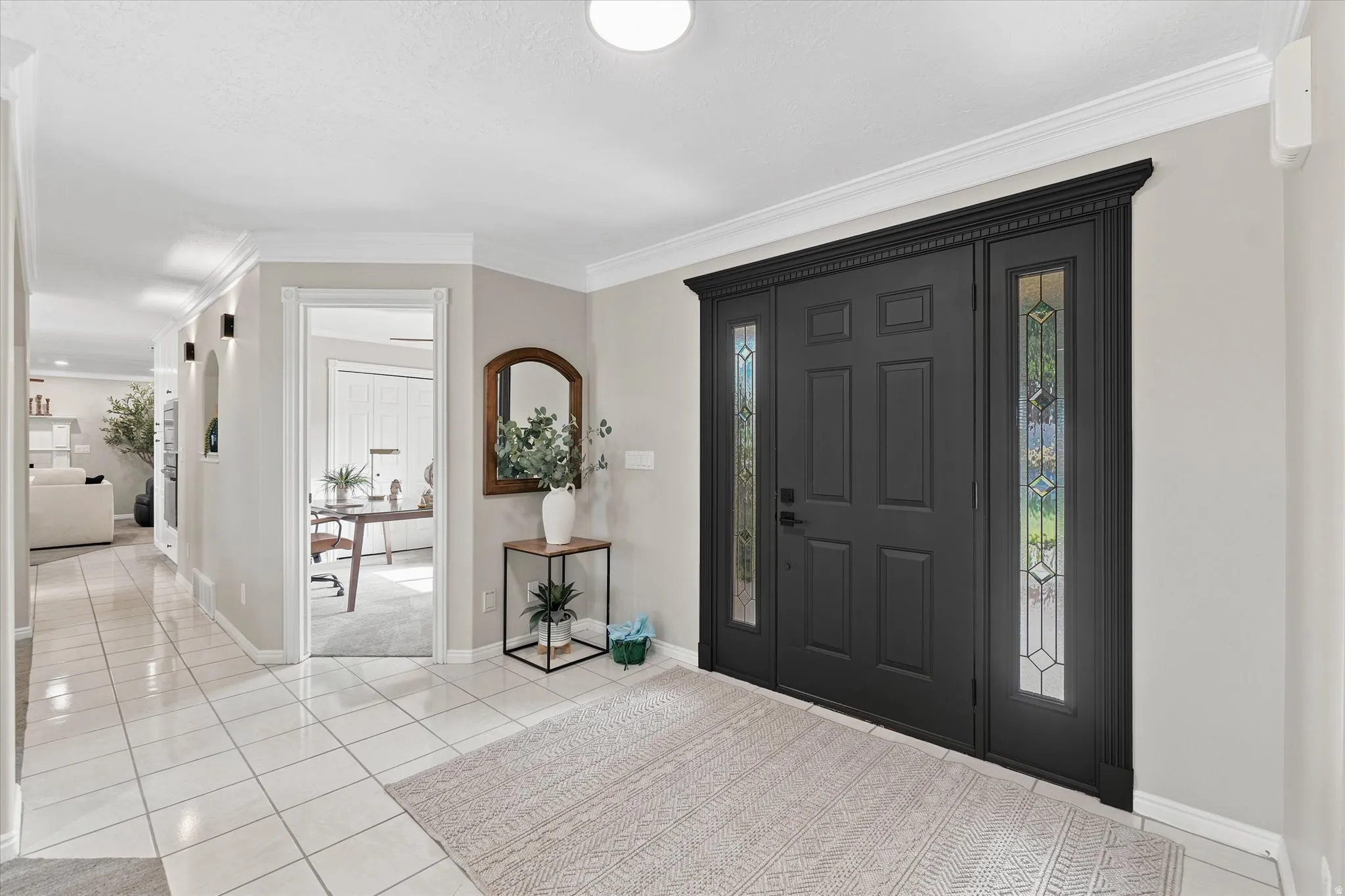 Grand entry with a dark paneled door, decorative glass sidelights, and detailed crown molding